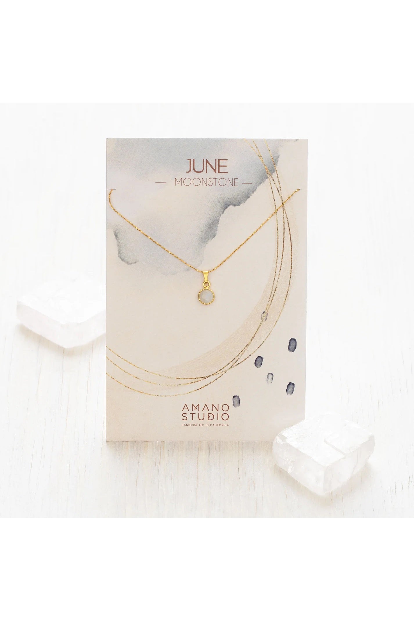 Birthstone necklace by Amano Studio, featuring a faceted gemstone on an 18-inch gold plated brass chain, displayed with crystals and description card.