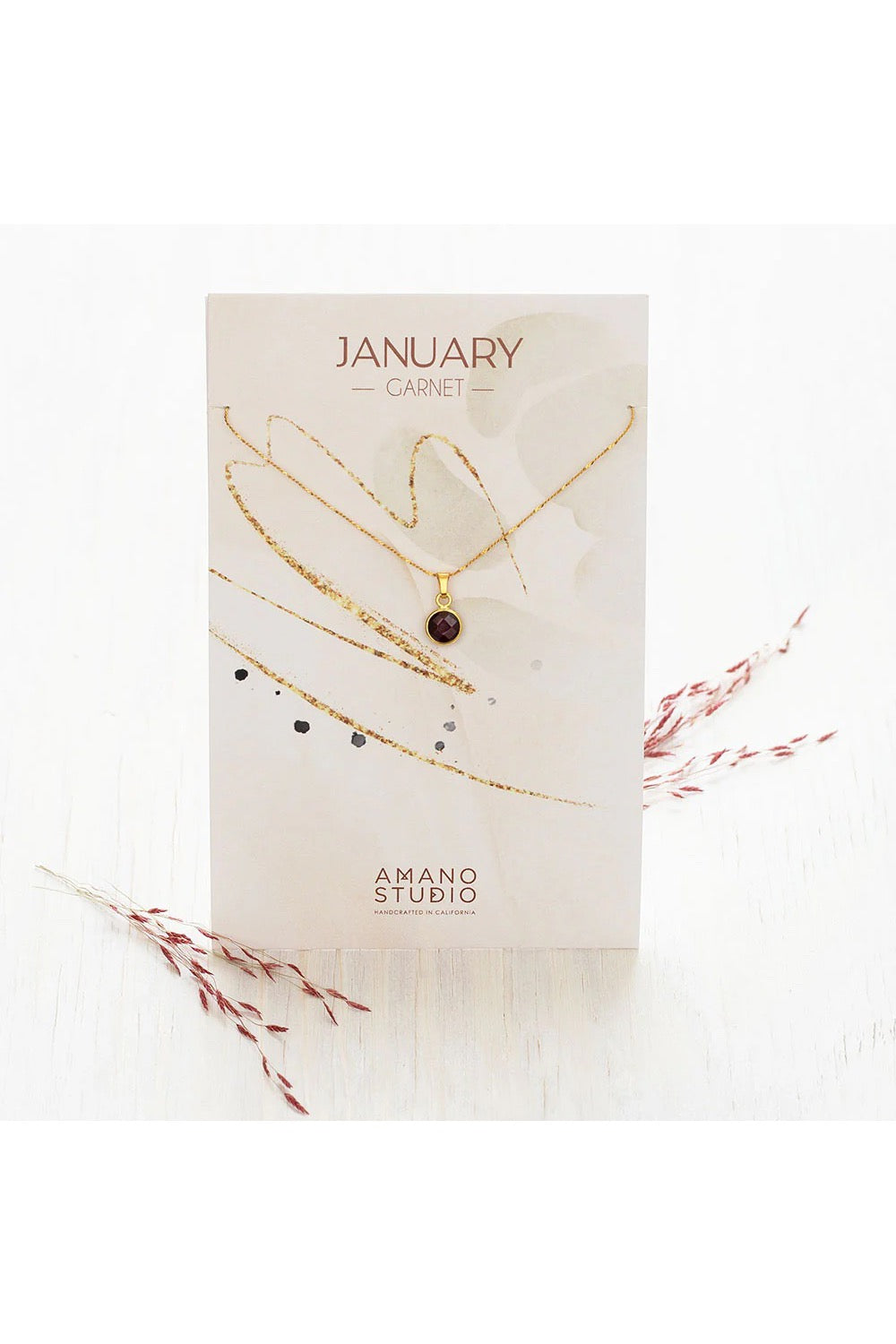 Birthstone necklace by Amano Studio, featuring a faceted gemstone on an 18-inch gold plated brass chain, displayed with crystals and description card.