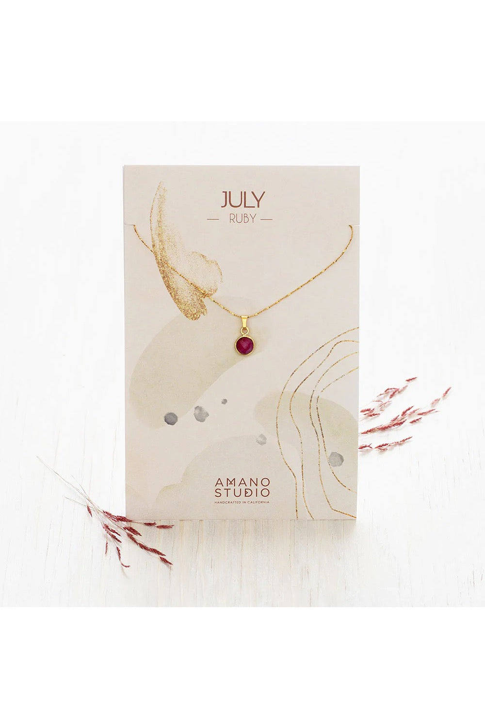 Birthstone necklace by Amano Studio, featuring a faceted gemstone on an 18-inch gold plated brass chain, displayed with crystals and description card.