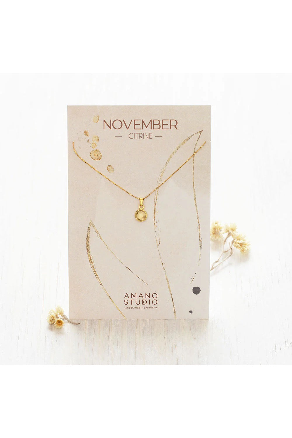 Birthstone necklace by Amano Studio, featuring a faceted gemstone on an 18-inch gold plated brass chain, displayed with crystals and description card.
